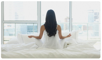 awoman-meditating-white-bed